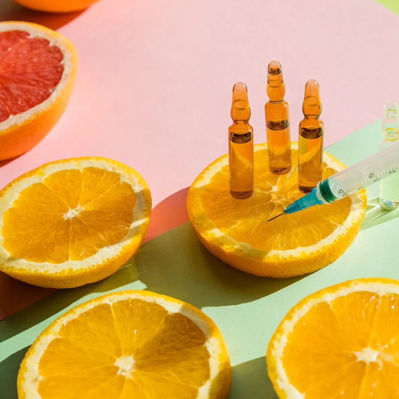 High dose vitamin C, ampule for injection with syringe and fresh juicy orange fruit slides. Concept